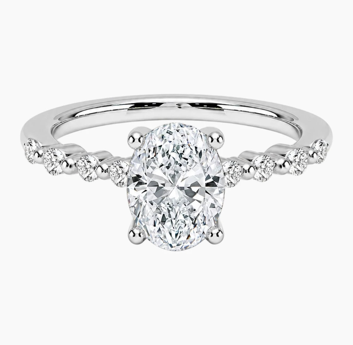 Oval-cut moissanite ring featuring an 18K white gold-plated band set with pavé diamonds; an elegant solitaire-style engagement ring.