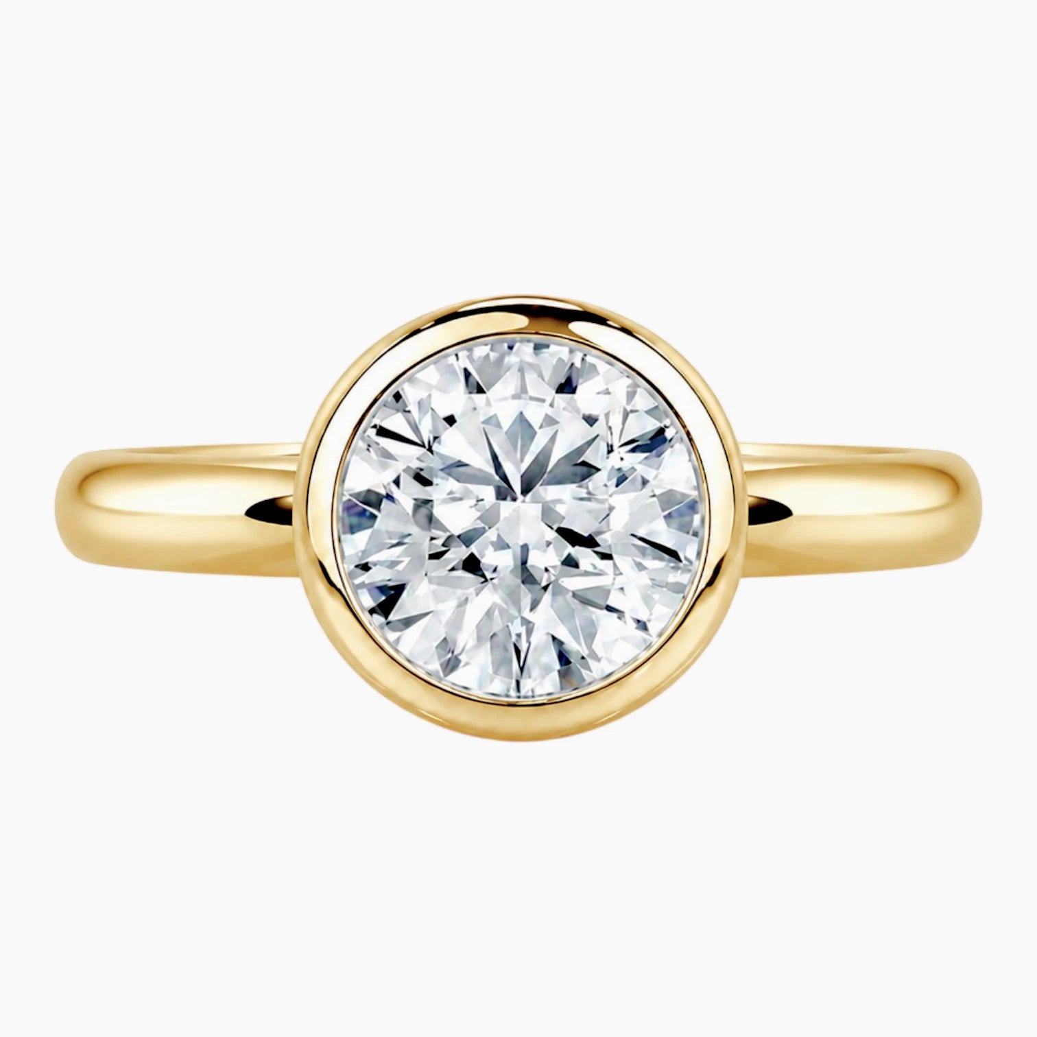 Round bezel moissanite engagement ring with a polished 2.6mm yellow gold band