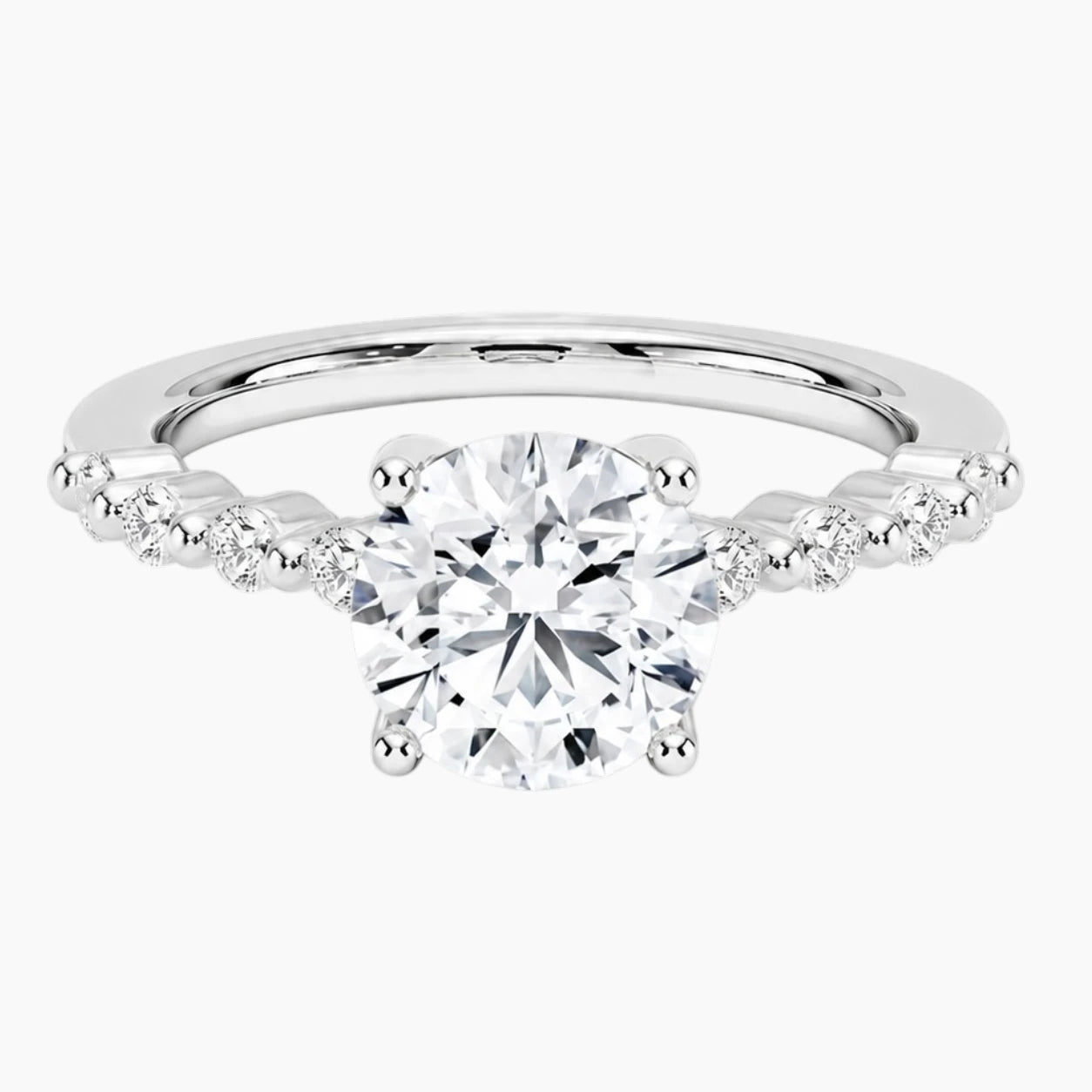 Round-cut moissanite ring featuring an 18K white gold-plated band set with pavé diamonds; an elegant solitaire-style engagement ring