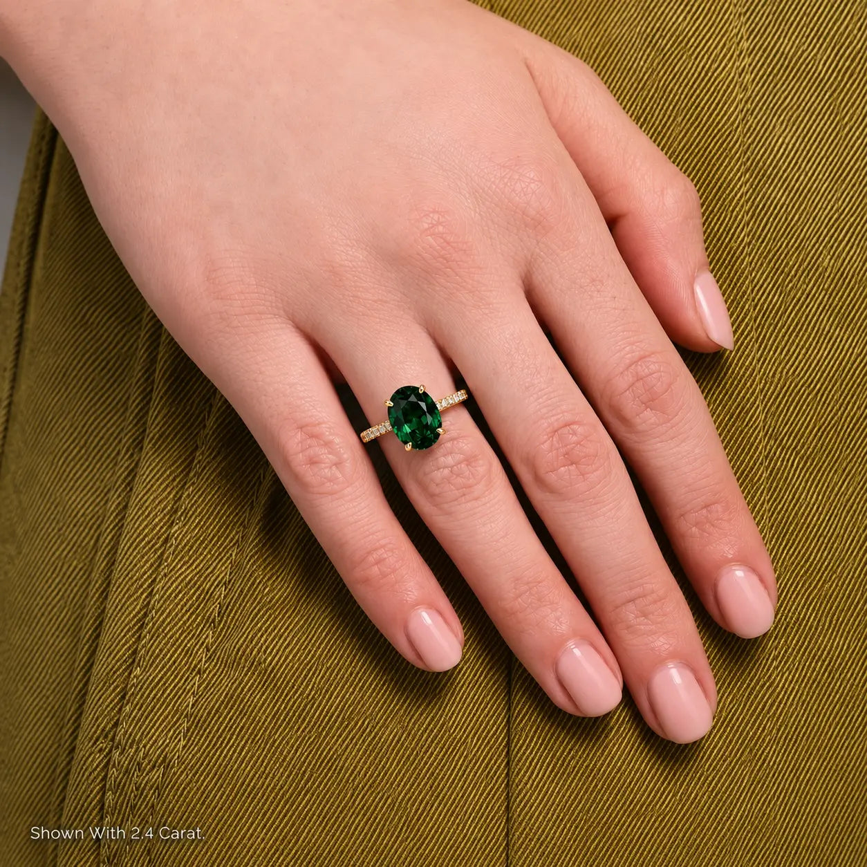 Close-up of a 2.4 carat oval emerald ring with a yellow gold pavé band