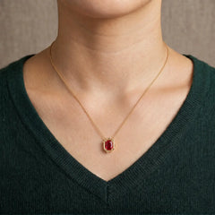 Woman wearing a 6×8mm ruby pendant necklace in 14K yellow gold, featuring a minimalist modern setting and fine gold chain.