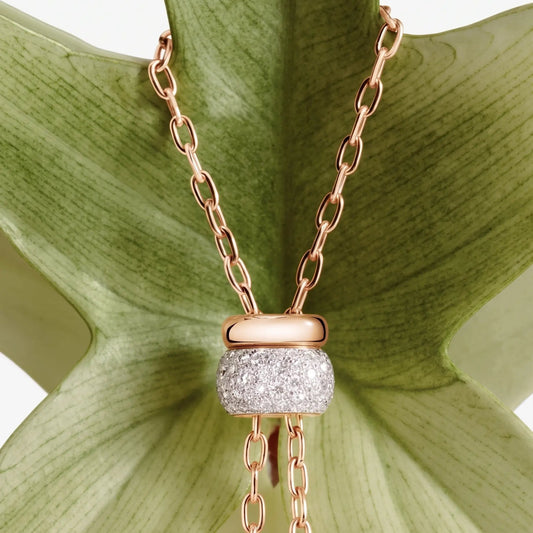 Gold chain necklace with pavé moissanite pendant displayed on a green leaf background