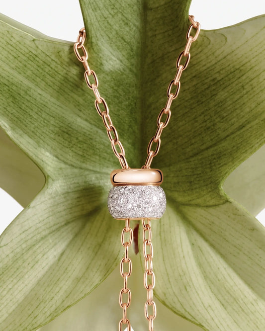 Gold chain necklace with pavé moissanite pendant displayed on a green leaf background