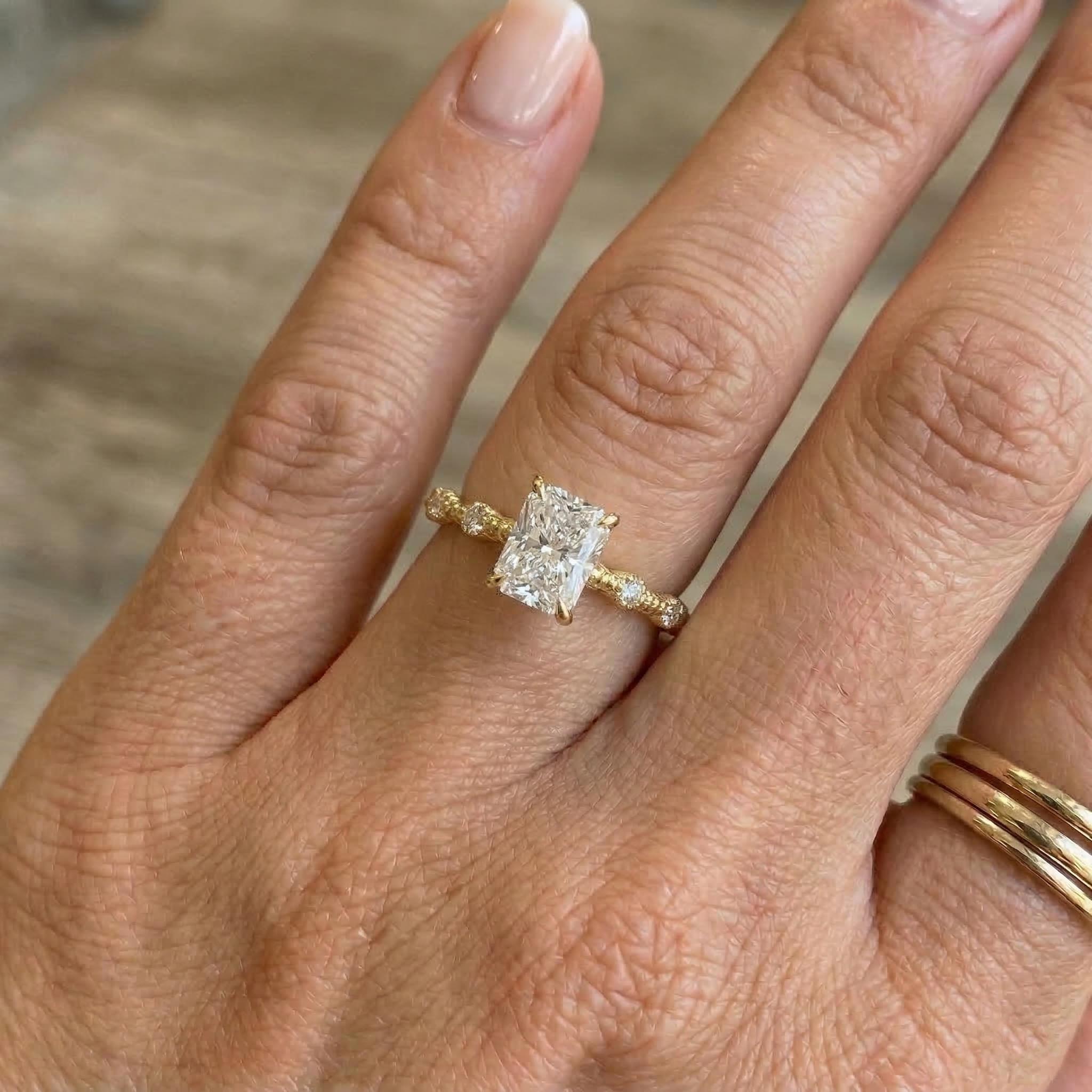 Radiant cut moissanite engagement ring with gold band on hand