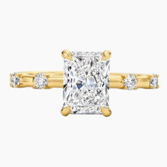 Radiant cut moissanite gold ring with side accent stones on white background