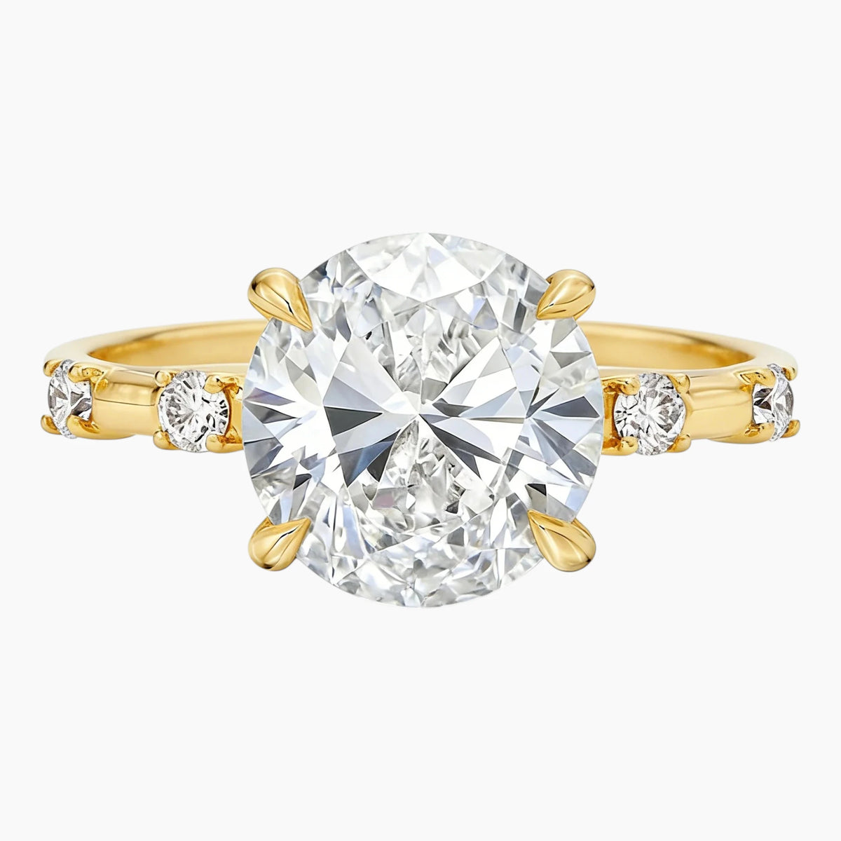 Oval moissanite engagement ring with gold band and side stones on white background