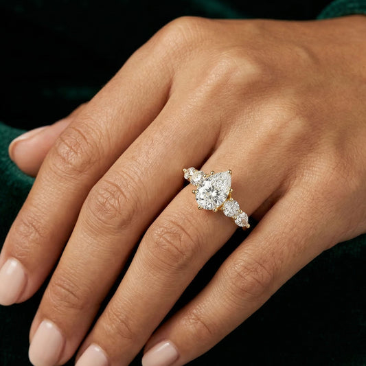 Hand wearing a gold moissanite engagement ring with brilliant center stone and side stones