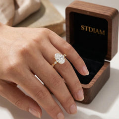 Oval moissanite engagement ring on hand with gold band, next to jewelry box
