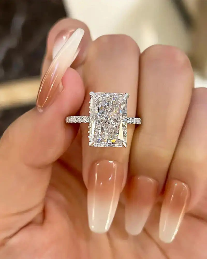 Radiant cut moissanite engagement ring with pave band on hand with long ombre nails