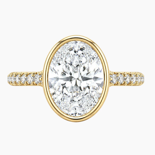Oval moissanite engagement ring with gold band and pavé accent stones