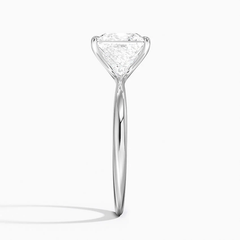 Side view of solitaire moissanite engagement ring with slim silver band on white background.