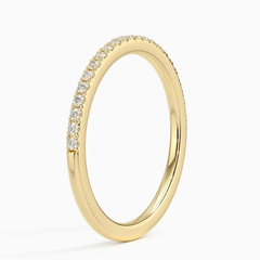 Thin gold band with small round moissanite stones in pavé setting on a white background.